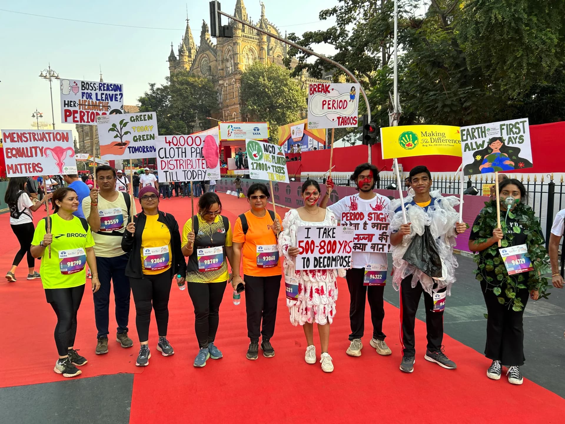 Team MTD on the red carpet with menstrual-health awareness placards at the Tata Mumbai Marathon