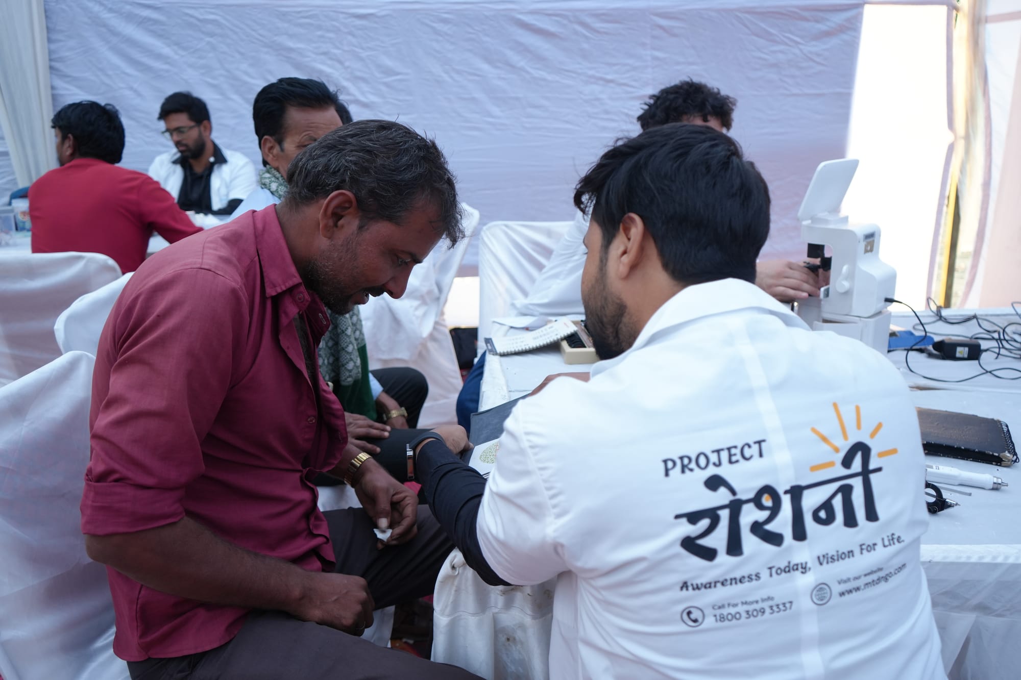 A health worker supporting a patient at a Roshni eye camp